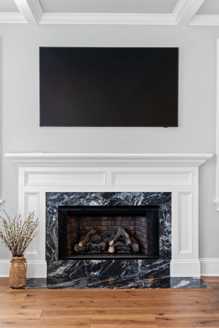 Black and white fireplace in Bucks County, PA with white mantel and mounted tv on light grey wall.