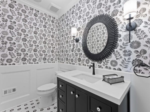 Modern bathroom in in Bucks County, PA with gray flowery wallpaper, white, sink and two wall sconces.