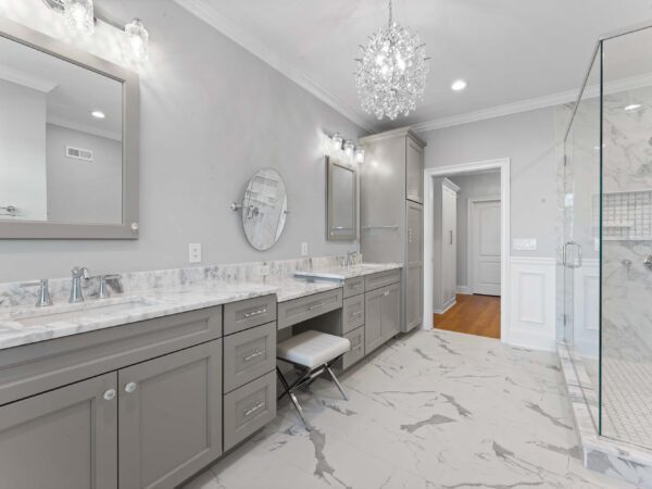 Modern bathroom in Bucks County, PA with light grey walls, double sinks, marble countertop, and mirrors with grey trim.