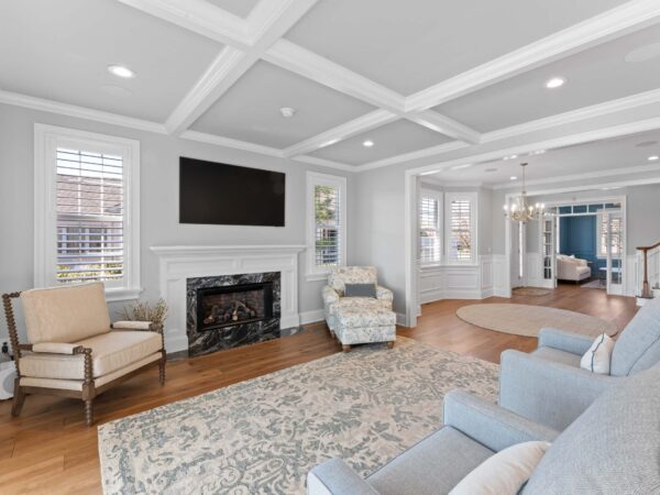 Modern living room in Bucky County, PA with light grey walls, marble fireplace, mounted tv, wood floors, and chairs.