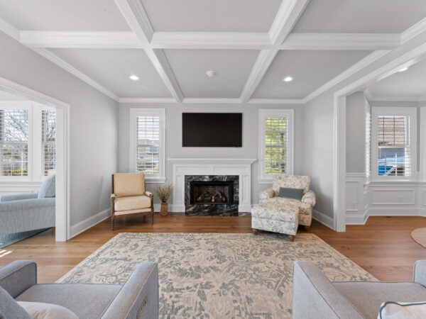 Modern living room in Bucks County, PA with light grey walls, marble fireplace, wood floors, and crown molding ceilings.
