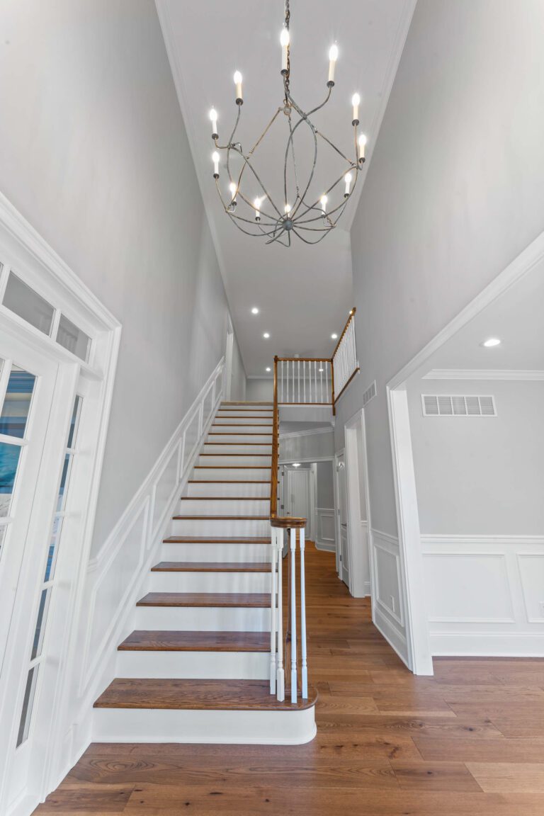 Modern staircase in Bucks County, PA with light grey walls, wood steps, white backing, and wood railing.