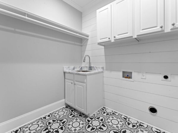 Modern laundry room in Bucks County, PA with light grey walls, white cabinets, and white sink with marble top.