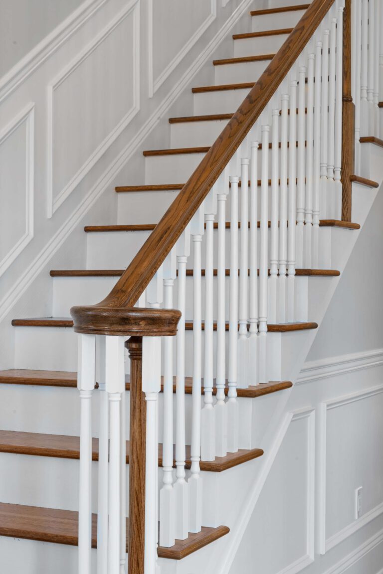 Modern staircase in Bucks County, PA with wood steps and railing, white walls and paneling.