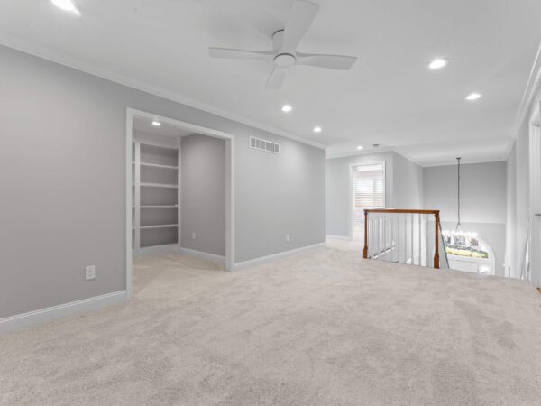 Modern upstairs landing in Bucks County, PA with light grey walls, light carpet, recessed lighting, and ceiling fan.