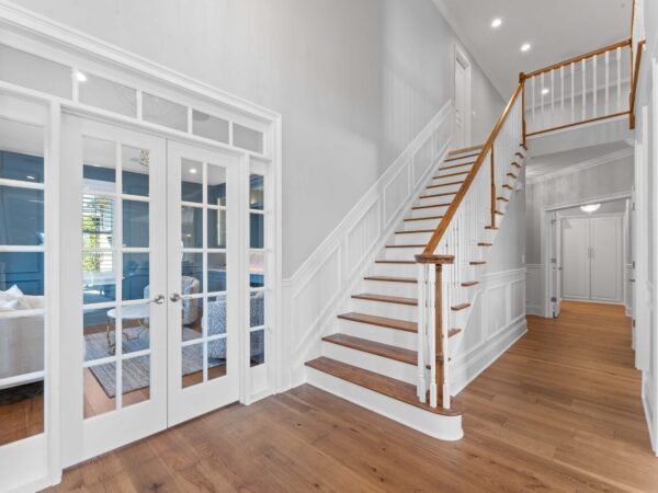 Modern stairway and hallway in Bucks County, PA with light grey walls, wood steps and railing, and white trim.