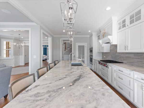 Modern kitchen in Bucks County, PA with white cabinets, marble countertops, stone backsplash, and white crown molding.